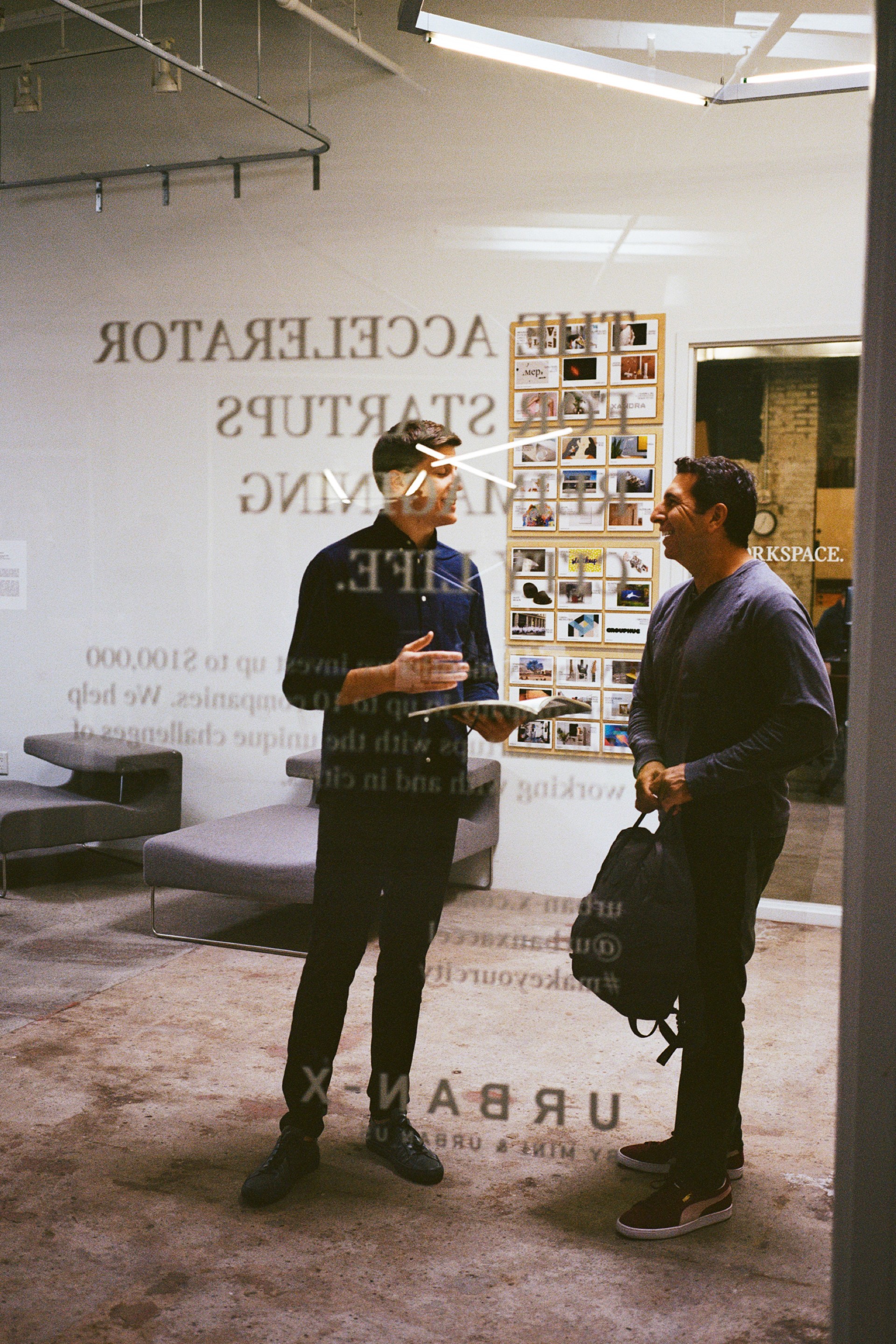 Two man are talking behind a glass wall.